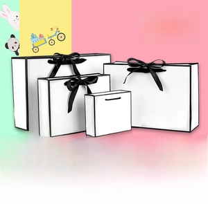 Detailed view of four white gift bags with black edges and decorative satin bows