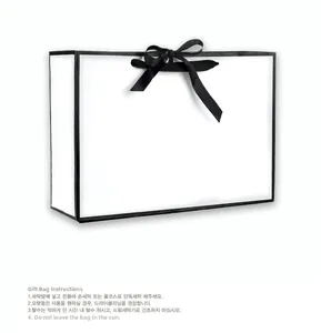 Detail of white gift bag with black ribbon bow showing care instructions label