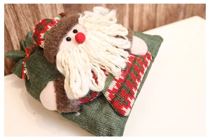 Close-up of a green burlap Christmas gift bag with a 3D plush Santa Claus doll decoration