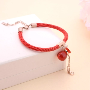 Handmade red cord bracelet with a rose gold lucky money bag pendant on a white gift box