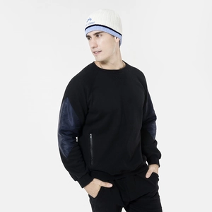 Detail of a color-block knit beanie with blue letter embroidery and contrast sleeves