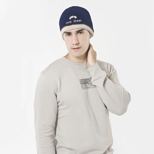 Detail of navy knit beanie with cool cheer embroidery paired with a gray sweater
