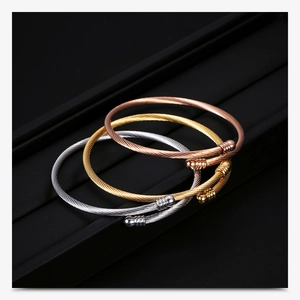 Detailed view of three 3mm stainless steel cable wire bracelets in silver gold and rose gold
