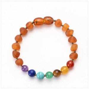 Vue à plat d'un bracelet en ambre pour bébé avec sept pierres de chakra colorées