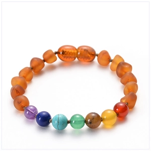 Détail macro du bracelet ambre pour bébé avec perles de sept chakras multicolores