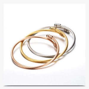 Detailed view of three twisted cable bracelets in rose gold, gold, and silver finishes