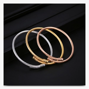 Detailed close-up of three-tone 18K gold cable wire bangles on black leather
