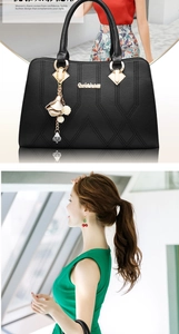Detail of black lychee texture leather tote with gold logo and floral pearl pendant