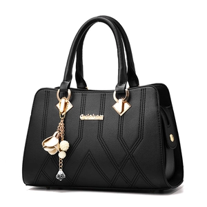 Elegant black textured leather handbag with gold hardware and pearl floral pendant