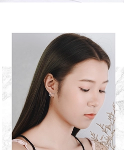 Close-up of minimalist silver cat stud earrings worn by a model to show product scale