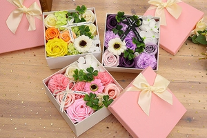 Close-up of square pink gift boxes with soap roses, carnations and silk ribbons