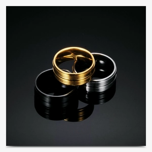 Detail of three minimalist 8mm stainless steel rings in gold, silver, and black colors