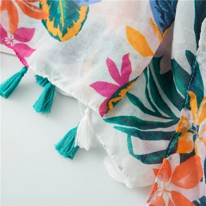 Detail of tropical floral cotton linen scarf featuring colorful tassels and vibrant leaves