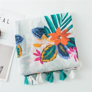 Detail of tropical floral print scarf with green palm leaves and colorful tassels