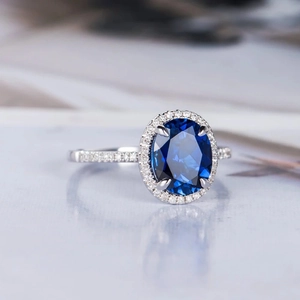Macro shot of oval royal blue sapphire ring with sparkling halo and micro-pave diamonds