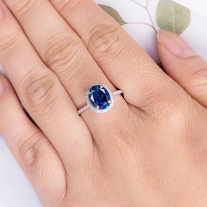 Elegant halo ring featuring oval blue sapphire and pavé diamonds on a silver band