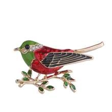 Detail view of bird brooch with colorful enamel and sparkling rhinestones on golden branch