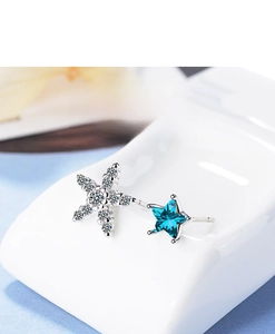 Macro detail of asymmetric blue star and sparkling silver snowflake stud earrings