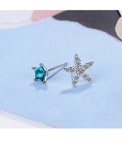 Macro shot of asymmetric silver star earrings with blue crystals and white zircons