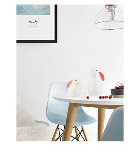 Detail view of minimalist white ceramic rabbit figurines with red polka dot ear patterns