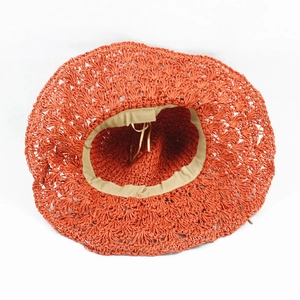 Detailed top view of handmade brick red straw hat with hollow lace weave and adjustable band