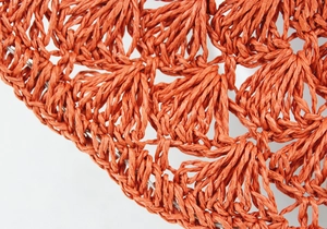 Macro detail of hand-woven orange sun hat with shell patterns and shaping wire edge