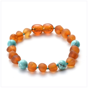 Detail of amber and turquoise beads baby bracelet on a clean white background