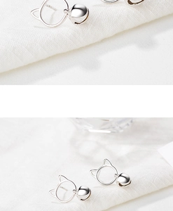 Detail of silver cat-shaped stud earrings featuring a hollow outline and hanging bell charm