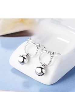 Close-up of silver cat ear stud earrings with bell charms on a white jewelry stand