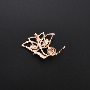 Elegant gold flower brooch with pearl accent showing back pin clasp and metal texture