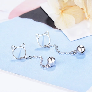 Elegant silver cat bell drop earrings with sleek metal chains on artistic floral background
