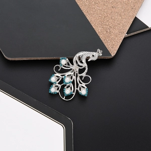Close-up of peacock brooch with white pearls and blue rhinestones on silver base