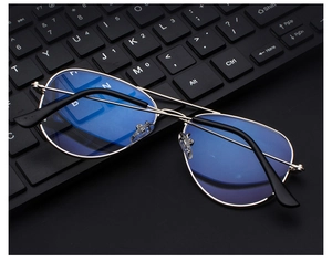 Silver metal aviator glasses with blue light blocking lenses on a computer keyboard