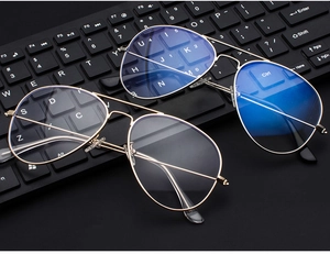 Golden aviator glasses frame with anti-blue light lenses on a black computer keyboard