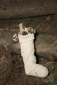 Close-up of cream knit Christmas stocking with cable pattern and white ribbon detail