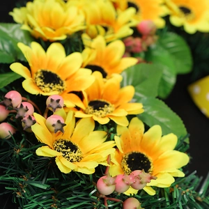 Artificial sunflower Christmas wreath with yellow blossoms and berries on black background