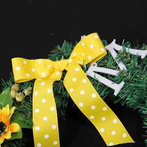 Artificial sunflower Christmas wreath with green pine needles and yellow polka dot ribbon bow