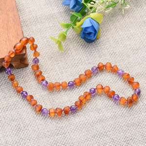 Baltic amber and amethyst beaded baby necklace on a natural linen background