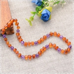Detailed macro view of Baltic amber beads mixed with purple amethyst on a textured background