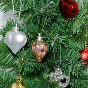 Close-up of matte and glossy heart ornaments hanging on green Christmas tree branches
