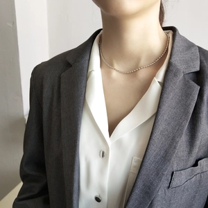 Close-up of minimalist 925 sterling silver bead choker on a model in a gray suit