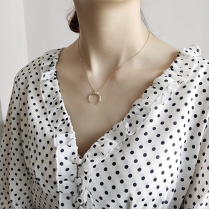 Close-up of sparkling crescent moon pendant on golden chain worn on a collarbone