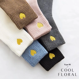 Detail of six cotton socks in diverse colors featuring gold heart embroidery accents
