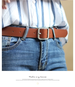 Detail of vintage brown leather belt with square silver buckle paired with blue jeans