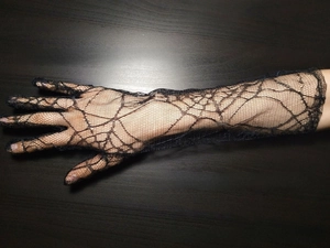 Detail of long black spider web lace gloves for Halloween cosplay fingerless costume style