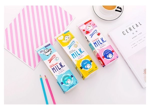 Flat lay of cute milk carton pencil cases in blue, yellow, and pink colors on a white desk