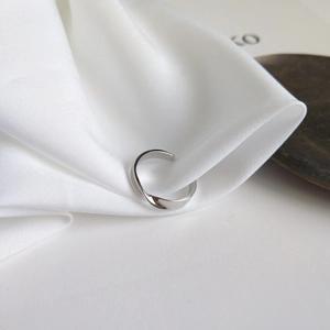Detailed view of S925 sterling silver twisted ring on elegant white silk fabric