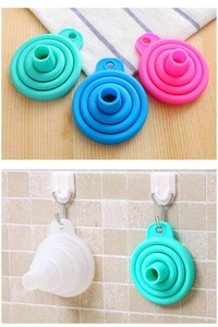 Detail view of colorful silicone collapsible funnels hanging on a tiled wall hook
