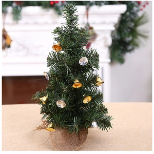 Miniature green Christmas tree with gold and silver bells on a burlap base for decor