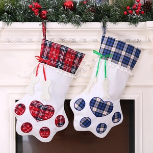 Plaid dog paw Christmas stockings with bone tags hanging on a festive fireplace